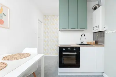 a kitchen with white cabinets and a black oven at Pastel Grove Suite - by Upstairs in Kraków