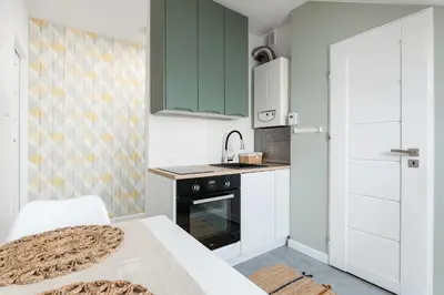 a small kitchen with green cabinets and a sink at Pastel Grove Suite - by Upstairs in Kraków