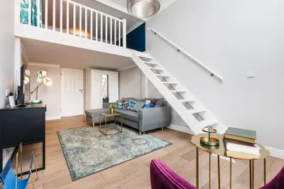 a living room with a couch and a staircase at Wawel Castle View - City Center Suite - by Upstairs in Kraków