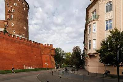 a large brick wall next to a building and a tower at Wawel Castle View - City Center Suite - by Upstairs in Kraków