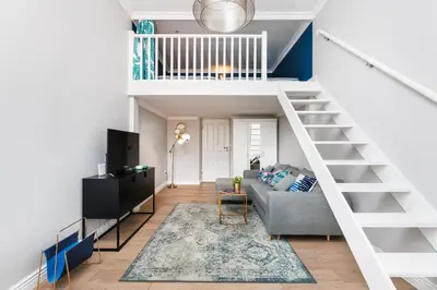 a living room with a couch and a staircase at Wawel Castle View - City Center Suite - by Upstairs in Kraków
