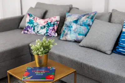 a couch with pillows and a table with a book at Wawel Castle View - City Center Suite - by Upstairs in Kraków