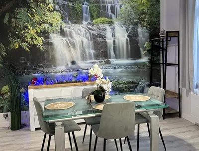 a table with chairs in front of a waterfall mural at Apartment near Old Town in Kraków