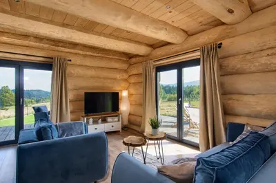 a living room with blue couches and a television at Domek w górach z balią jacuzzi Asina Chata Zawoja in Zawoja