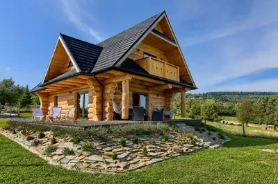 a log cabin with a gambrel roof at Domek w górach z balią jacuzzi Asina Chata Zawoja in Zawoja