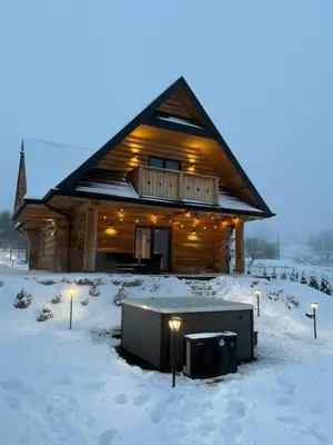 a log cabin with a tv in the snow at Domek w górach z balią jacuzzi Asina Chata Zawoja in Zawoja