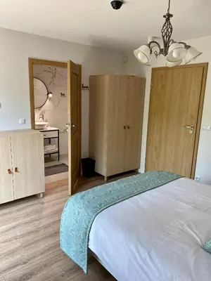 a bedroom with a bed and wooden cabinets and a bathroom at Stara Plebania in Ponice