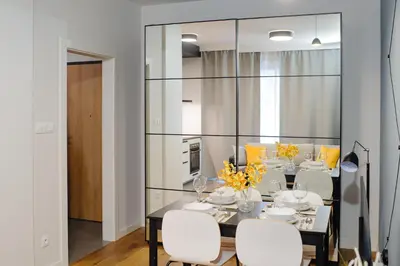 a dining room with a table and chairs and a mirror at Like Home Apartments in Kraków