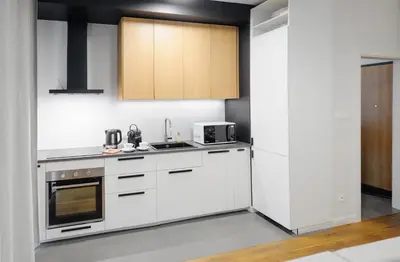 a kitchen with white appliances and wooden cabinets at Like Home Apartments in Kraków