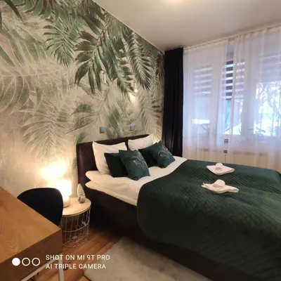 a bedroom with a bed with a palm leaf mural at Seventh House in Kraków