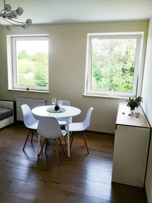 a white table and chairs in a room with two windows at Apartament Hubertus in Bochnia