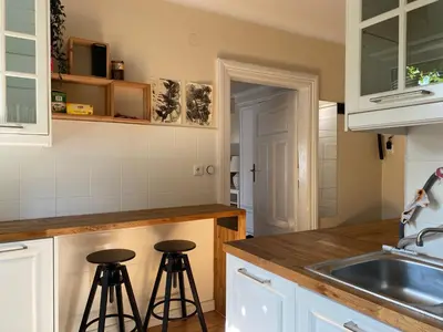 a kitchen with a sink and two bar stools at Apartament na starej Krowodrzy in Kraków