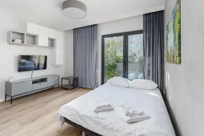 a white bedroom with a bed and a television at Park Krowoderski Comfort Apartment by BookingHost in Kraków