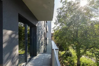 a balcony with glass doors and a tree on the side of a building at Park Krowoderski Comfort Apartment by BookingHost in Kraków