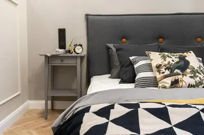 a bedroom with a bed with a black headboard and a table at Nobel Apartment - BEST LOCATION! in Kraków