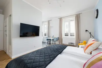 a bedroom with a large bed with a television on the wall at Modern Studio Kazimierz for 4 Guests only 1 km to Wawel Castle by Noclegi Renters in Kraków