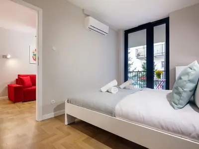 a bedroom with a bed and a window and a red chair at Tyzenhauz Apartments Vistula with Parking in Kraków
