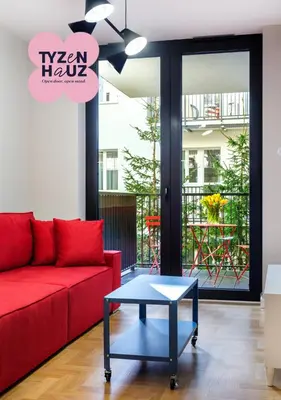 a living room with a red couch and a table at Tyzenhauz Apartments Vistula with Parking in Kraków