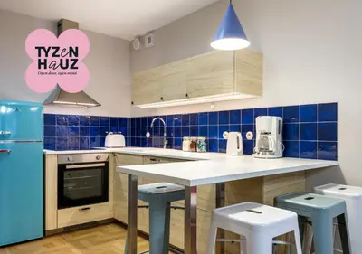 a kitchen with blue tiled walls and a counter with stools at Tyzenhauz Apartments Vistula with Parking in Kraków