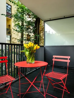 a red table with a vase of flowers on a balcony at Tyzenhauz Apartments Vistula with Parking in Kraków