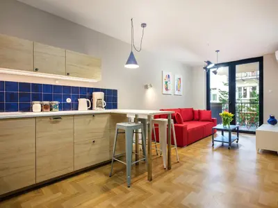 a kitchen and living room with a red couch at Tyzenhauz Apartments Vistula with Parking in Kraków