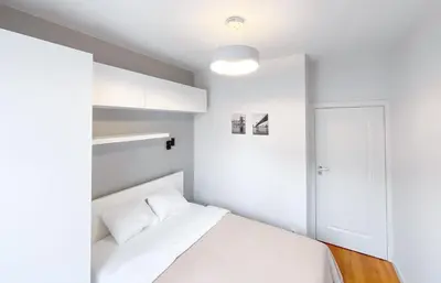 a white bedroom with a white bed and a door at Like Home Apartments in Kraków
