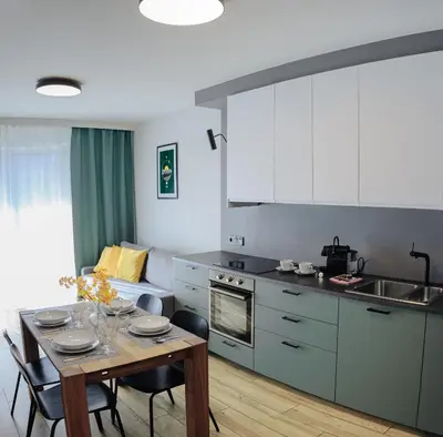 a kitchen with a table with chairs and a dining room at Like Home Apartments in Kraków