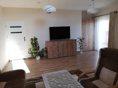 a living room with a flat screen tv on a cabinet at Noclegi Pod Lasem in Kraków