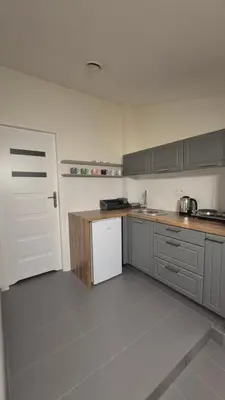 a kitchen with gray cabinets and a white refrigerator at Noclegi Pod Lasem in Kraków