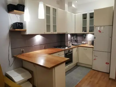 a kitchen with white cabinets and a wooden counter top at Cozy spacious apartment with balcony in Kraków