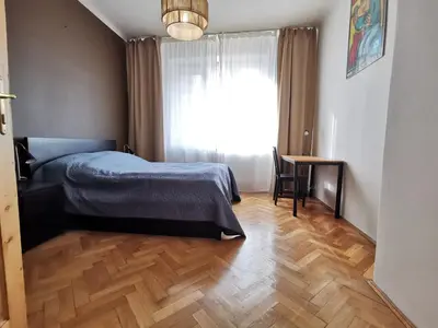 a bedroom with a bed and a desk and a window at Cozy spacious apartment with balcony in Kraków