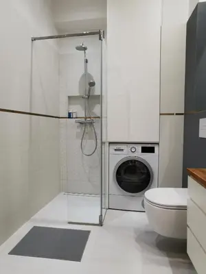 a bathroom with a shower and a washing machine at Cozy spacious apartment with balcony in Kraków