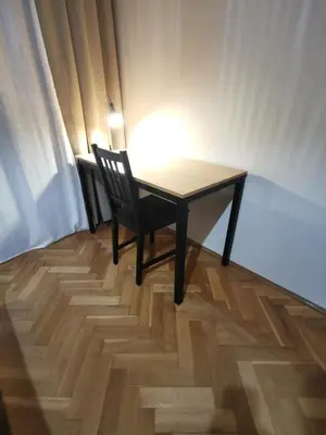 a table and a chair on a wooden floor at Cozy spacious apartment with balcony in Kraków