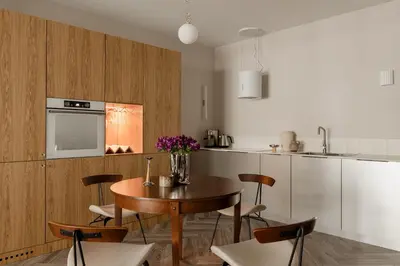 a kitchen with a wooden table and chairs and a kitchen with white cabinets at Sage Apartment in Kraków