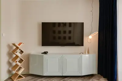 a white cabinet with a tv on a wall at Sage Apartment in Kraków