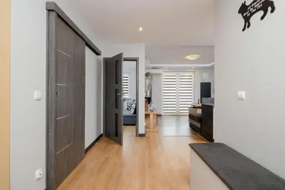 a hallway with white walls and a wooden door at Spacious Apartment for 6 Guests in Krakow with Home Office by Noclegi Renters in Kraków
