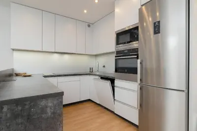 a kitchen with white cabinets and a stainless steel refrigerator at Spacious Apartment for 6 Guests in Krakow with Home Office by Noclegi Renters in Kraków