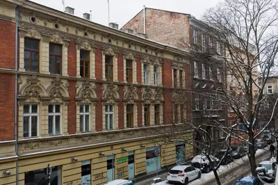 a large brick building with cars parked in front of it at Beautiful & Cozy Apartment next to Main Market in Kraków