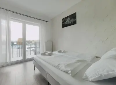a white bedroom with a bed and a large window at Klimeckiego 8a by Homeprime in Kraków