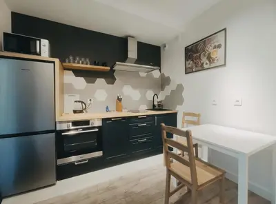 a kitchen with black cabinets and a table and a refrigerator at Klimeckiego 8a by Homeprime in Kraków