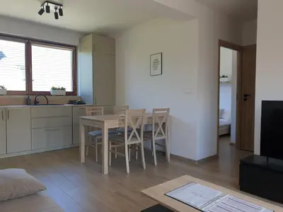 a kitchen and living room with a table and chairs at Near the airport- Apartments in Kraków