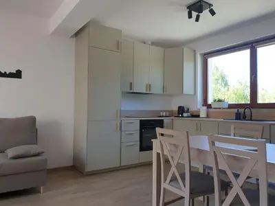 a kitchen with white cabinets and a table and chairs at Near the airport- Apartments in Kraków