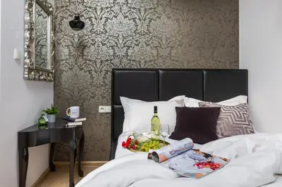 a bed with a tray of food and a bottle of wine at Fragola Apartments Piłsudskiego 11 in Kraków