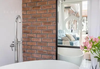 a bathroom with a brick wall and a mirror at Fragola Apartments Piłsudskiego 11 in Kraków