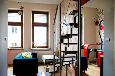 a living room with a blue couch and a spiral staircase at Studio in the center -easy access from the airport in Kraków