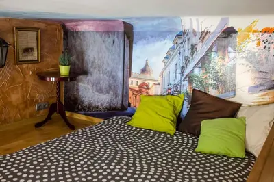 a bed with green pillows in a room with a mural at Studio in the center -easy access from the airport in Kraków