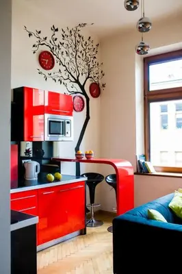 a kitchen with red cabinets and a tree on the wall at Studio in the center -easy access from the airport in Kraków