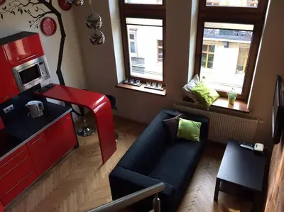 a living room with a blue couch and a kitchen at Studio in the center -easy access from the airport in Kraków