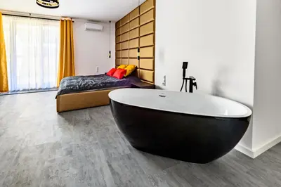 a bathroom with a black tub and a bed at Apartament 5th floor in Kraków