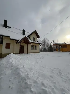 a house with snow on the ground in front of it at Domek na Stasince in Sidzina
